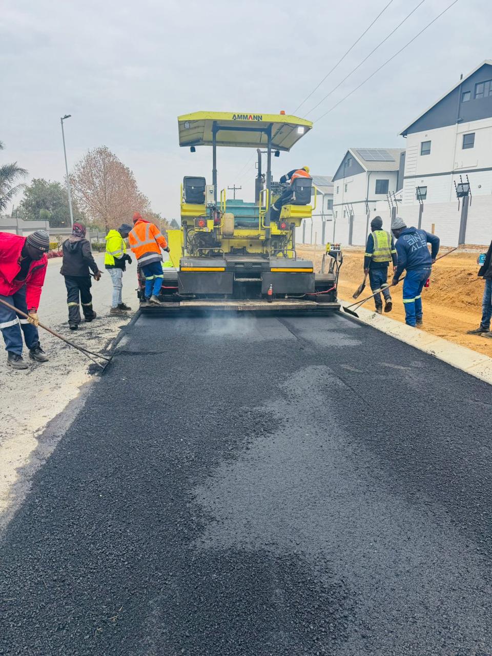 Paving crew working behind the asphalt paver on the new road surface
