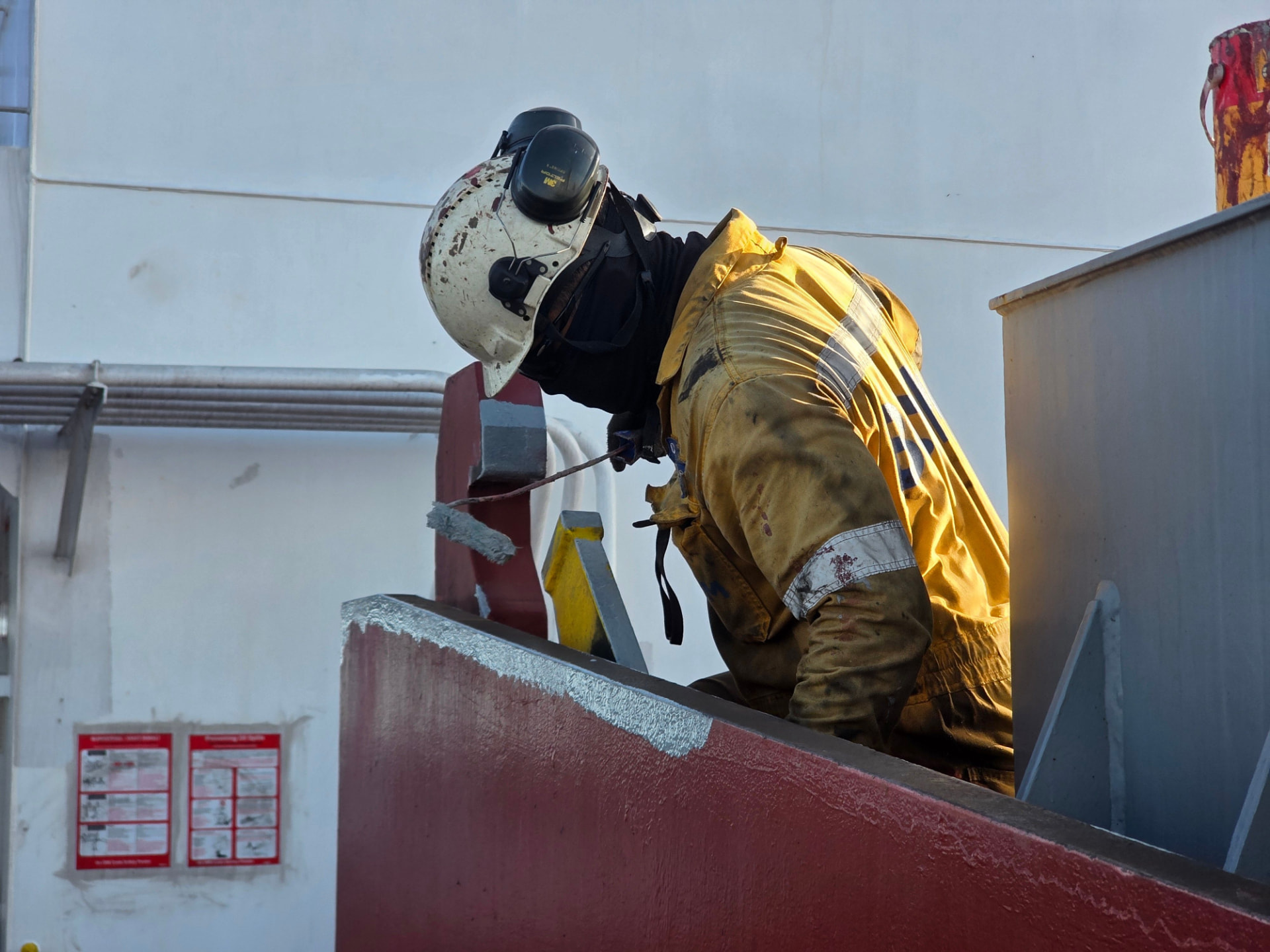 Maintenance worker in hard hat and high-visibility jacket working at height on site