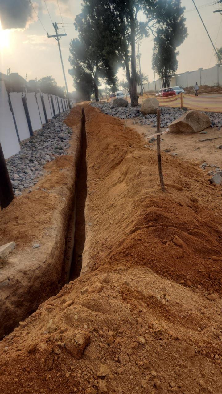 Long service trench with pipework laid alongside the boundary wall