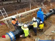Team completing a pipeline joint connection within a shored excavation