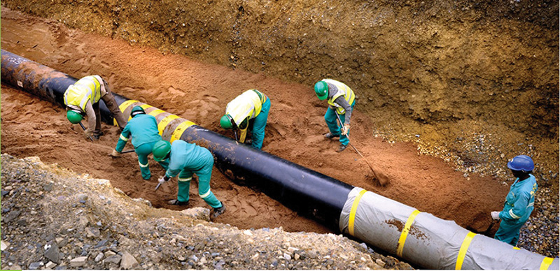 Site crew installing large pipeline sections in an open trench